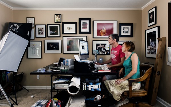 We use our entire house as a studio: to shoot videos and photographs in, to construct sculptural installations in and to edit and manage our art practice.  Here we are sitting at the work computer amidst the lights and other equipment. Behind us is a photograph from the House/hold series of our dog, Penny, titled “Cerebus.”  