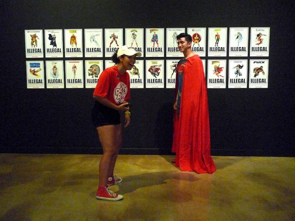 Superman Impersonator in front of installation of 24 “wanted posters” in the Illegal Superheroes Series 1 (2012) by The Department of Illegal Superheroes (ICE DISH)