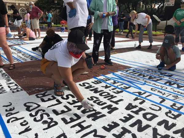 Volunteers paint their signatures onto Sedrick and Letitia Huckaby's temporary street painting downtown Fort Worth, July 27, 2020. Photo Credit, Adam Werner