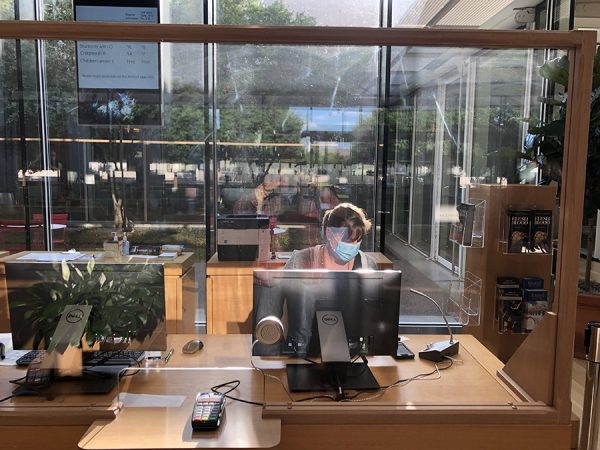 A masked employee behind a plexiglass window at the Kimbell Art Museum, July 24, 2020
