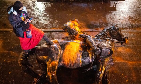  A protester stands over a toppled statue of Theodore Rosevelt during a protest Sunday in Portland, Oregon. Photograph- Nathan Howard/Getty Images