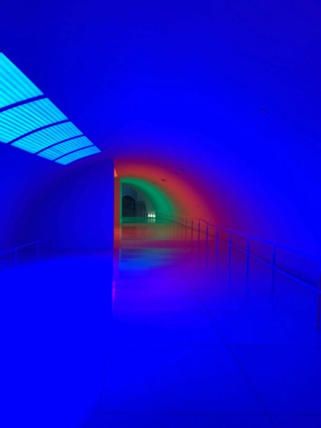 El pasillo casi tubular de una galería es iluminado por una sucesión de luces neón de distintos colores.