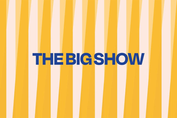 Sobre un fondo a rayas desiguales de color amarillo y rosa pálido, está escrito en letras azules “THE BIG SHOW”.