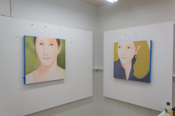 Two portrait paintings sit on either side of two walls in the studio of Wichita Falls artist Yasuyo Maruyama