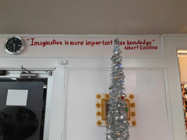 Sobre una pared blanca con molduras se lee en letras rojas “Imagination is more important than knowledge” (La imaginación es más importante que el conocimiento), Albert Einstine [sic].