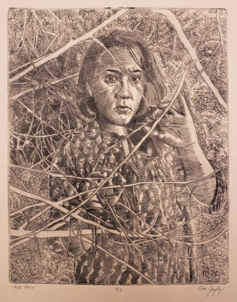 A drypoint print of a woman. She is standing behind branches that partially cover her body.