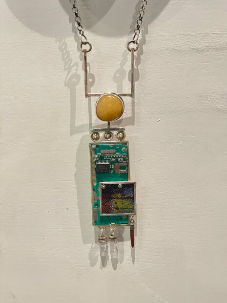 A sculptural necklace, featuring a polished stone and circuit boards.