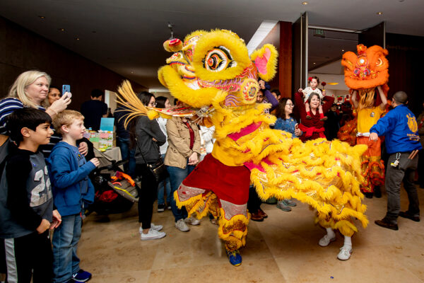 A crowd looks on as performers dressed in a traditional Chinese Lion costume perform.