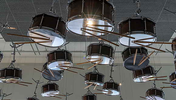 Detail of an installation by artist Anri Sala of snare drums suspended upside down from the ceiling with drum sticks