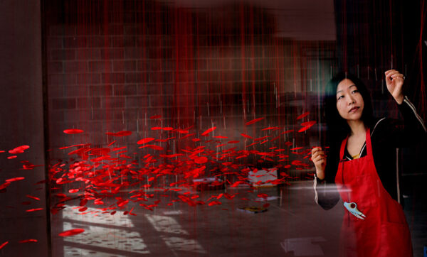 A color photograph by ROMAIN BLANQUART of artist Beili Liu installing a work of art.