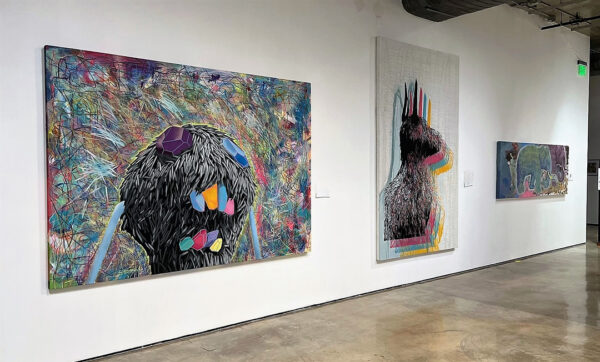 A photograph of three large scale paintings by Ernesto Ibanez. 