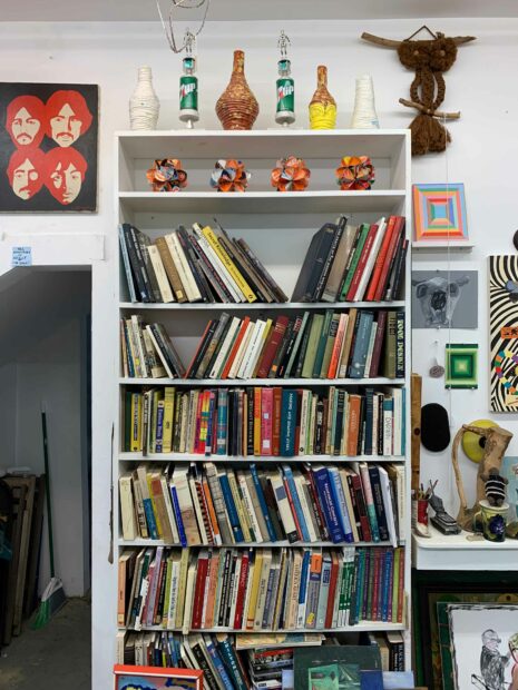 A photograph of a crowded store, featuring books, paintings, and other objects on shelves and the store's floor.