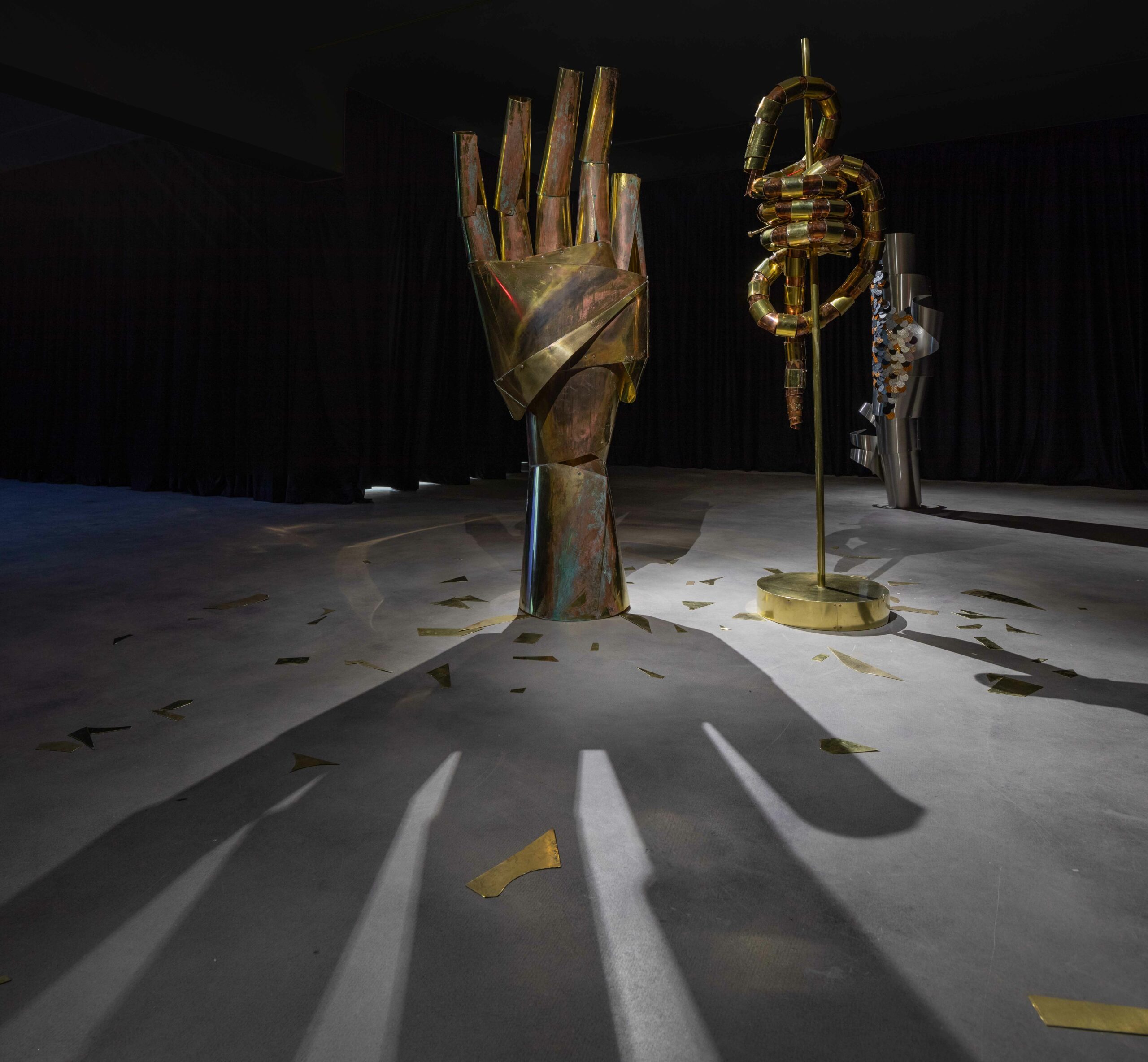 Installation detail of three large scale metal sculptures. One sculpture is a large human hand, the other are two organic shapes