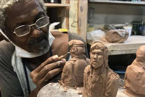 Photograph of Earnest Snell in the pottery studio working on a clay figure.