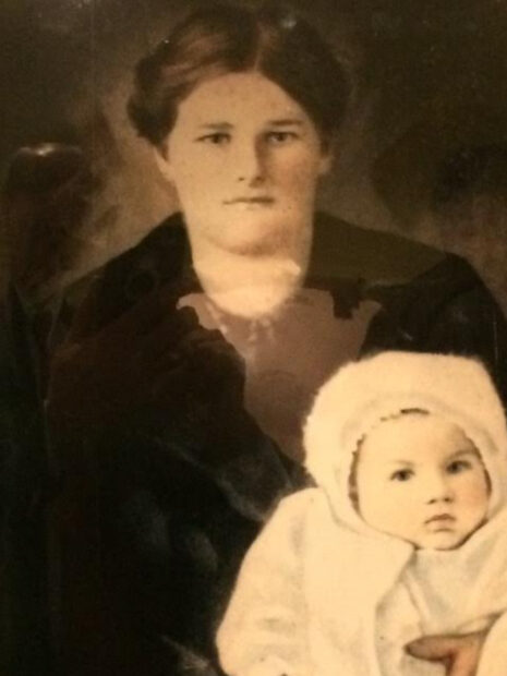 Old photograph of a woman holding a baby that is bundled up in a white coat