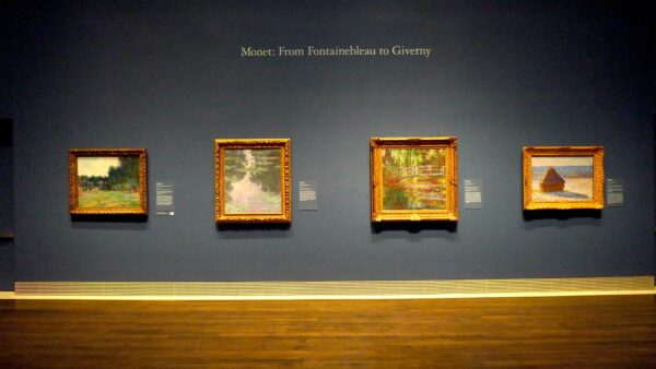 Installation shot of Impressionist exhibition. Four paintings by Monet against a blue wall
