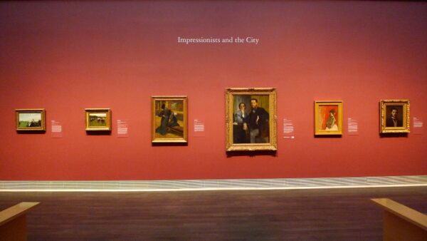 Installation view of six impressionist paintings on a red wall