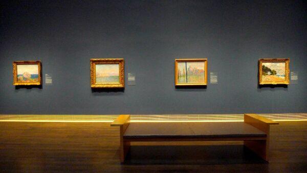 Installation view of four paintings by Monet on a blue wall