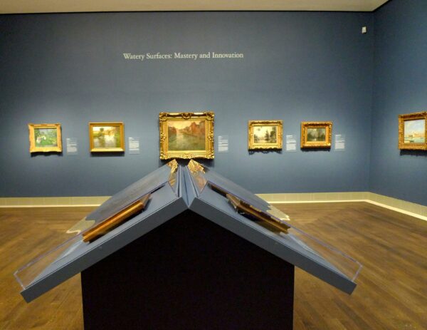 Installation view of Impressionist paintings on a light blue wall