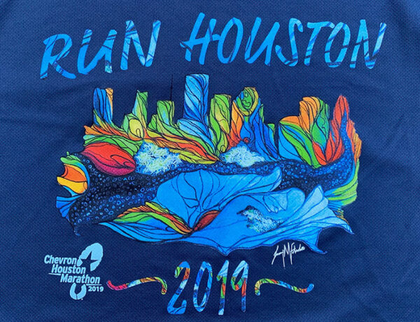 A close-up photograph of a blue athletic shirt with text and a printed image. The printed image depicts the Houston skyline filled in with brightly colored organic shapes and lines. Above the image is the text, "Run Houston." Below the image is the year "2019", a small logo for Chevron Houston Marathon, and the artist's signature.