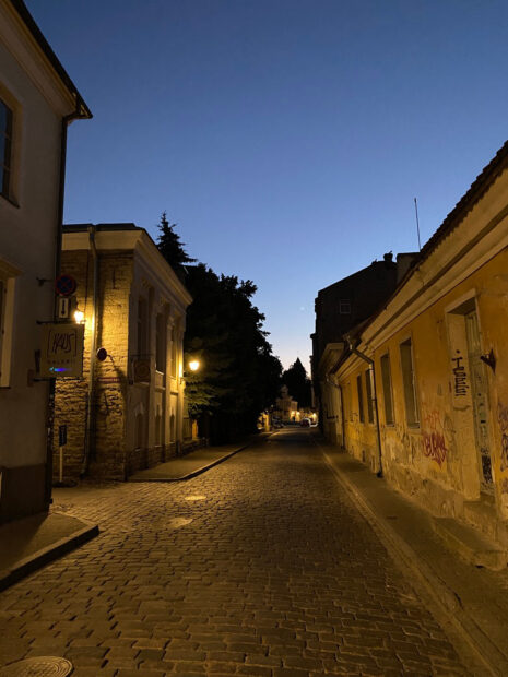 Photograph of the town of Tallinn, Estonia. This is a cobble paved street, with buildings on either side of it.