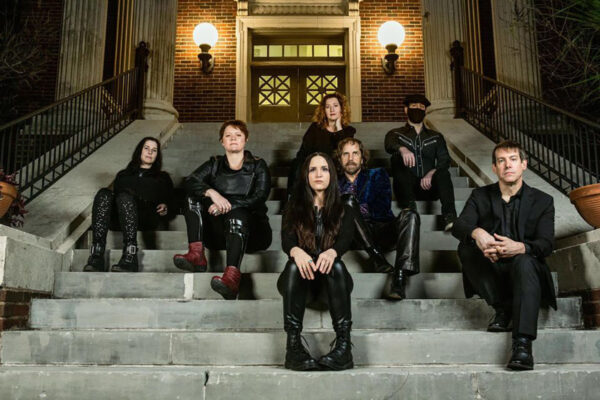 A photograph of the seven members of Two Star Symphony dressed in black and seated on a staircase.