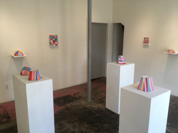 A photograph of many colorful artworks on pedistals.