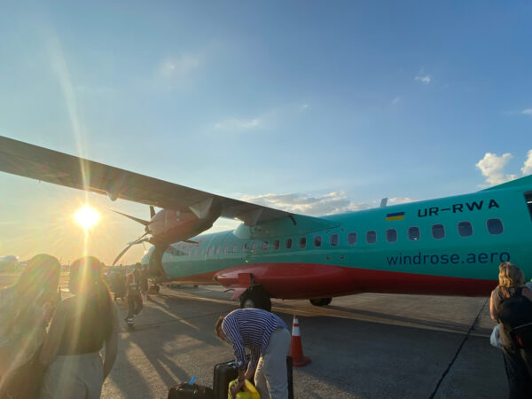 Image of a green and red plane with passengers on the tarmac