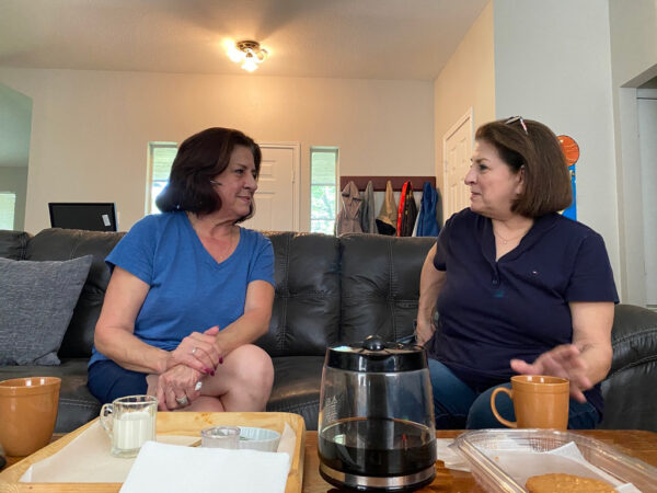 Two women sitting on a living room couch talking with each other. The women are twins and are the author's paternal aunts.