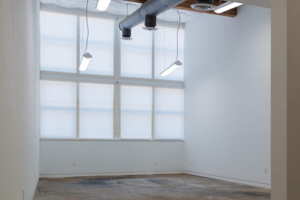 A large, empty studio space. There are windows on one end of the white-walled room.
