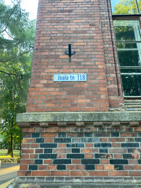 A street sign indicating the address of the residency against the brick wall of the building itself.
