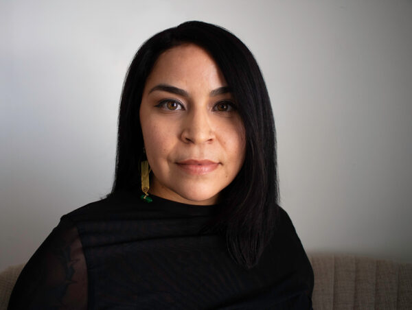 A headshot of Mari Hernandez. She wears a black top and looks directly at the camera with a slight smile.