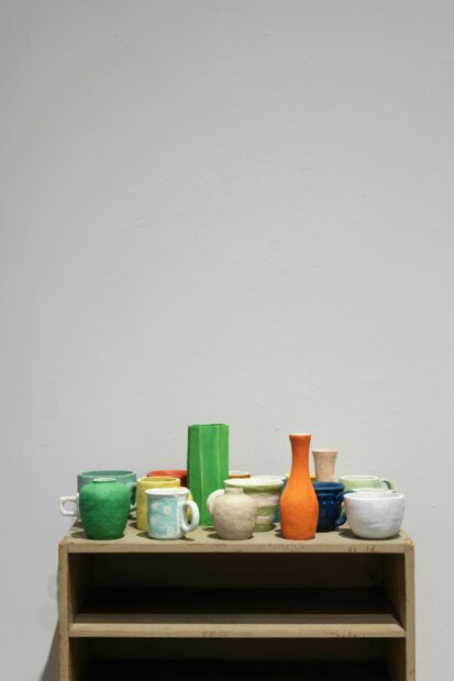 Exhibition image of a luster of ceramic mugs and vases of various colors