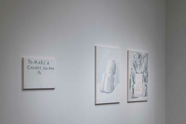 Image of three works on a white wall. The works are all gestural, except the one on the left which has the phrase "to make a change you have to:"