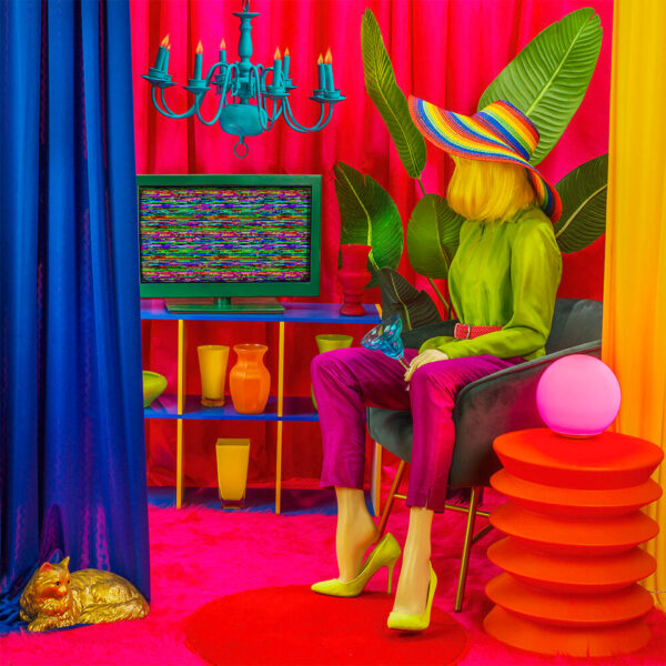 Image of a woman sitting in a chair in a room filled with technicolored objects.