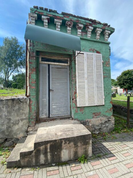 An abandoned and stand alone structure with green paint and white shutters and doors int he Valga old town
