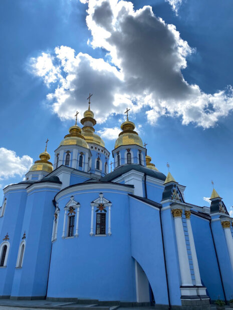 Image of a cathedral painted bright blue with red details and golden domes