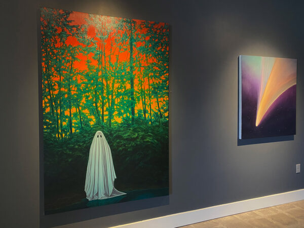 An installation view of two works of art hanging on a gray wall. The paintings are by Adam Fung. The one on the left is of a cloaked figure standing in front of a bushes and trees. Behind the trees looms a vibrant red sky. On the left is a smaller painting of outer space with a deep purple sky and what appears to be a meteor traveling across the sky. 