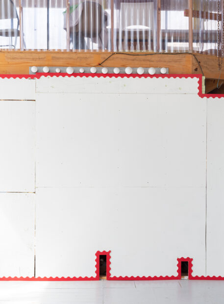 A white wall with red trim around the top, bottom, and holes in the wall.