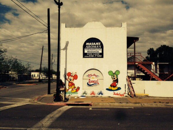 Photo of two images of Mickey Mouse painted on both sides of a white wall of a downtown Brownsville building.