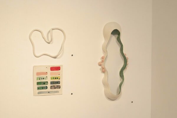 A grouping of ceramic sculptures of various shapes and sizes hanging on a white wall.