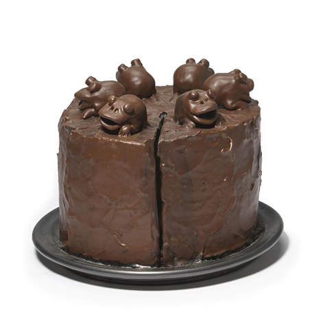 A brown cake, on top of which sit brown frogs.