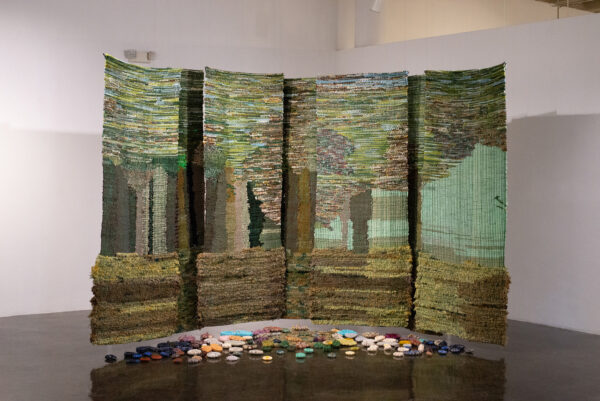 Installation of a woven textile piece that hangs in the space and suspended just above the ground