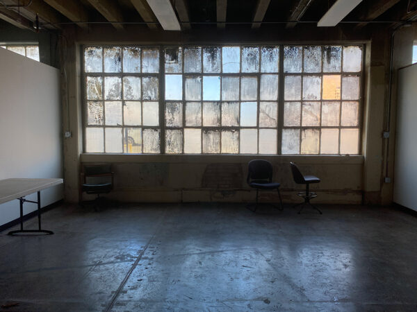 A photograph of a communal space inside Lancaster Lofts. The space features large windows and a concrete floor.
