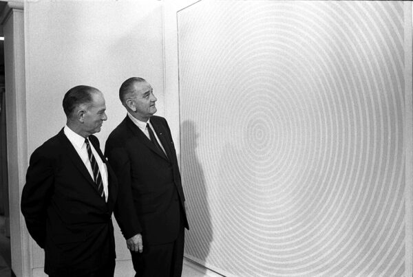 A black and white photograph of President Lyndon B. Johnson with Senator J. William Fulbright looking at a large abstract work of art.