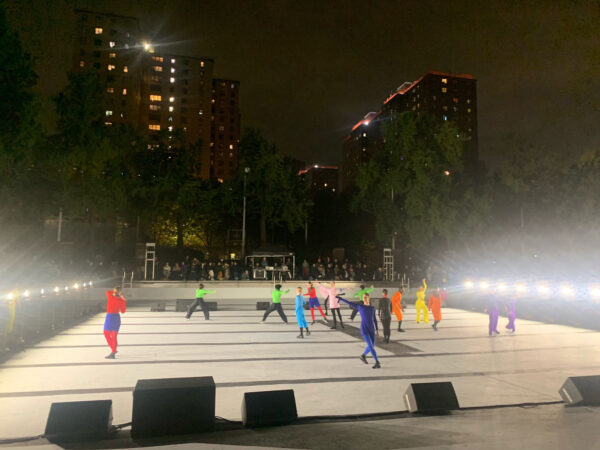 Photo of dancers performing at night on an outdoor stage in New York City