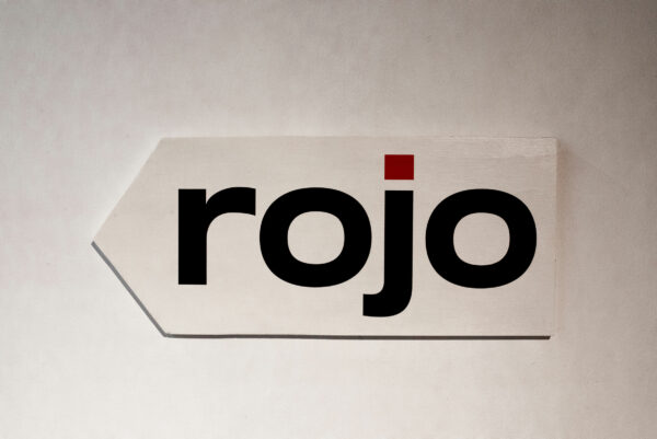the gallery sign which is a white arrow pointing to the left with the words "rojo" in black letters