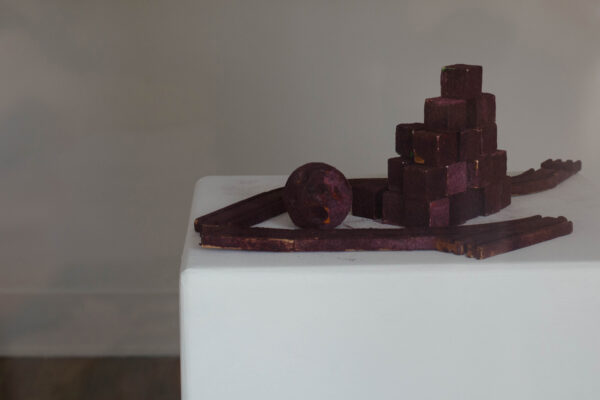Small sculptural objects like a ball and blocks covered in plum covered dust flocking
