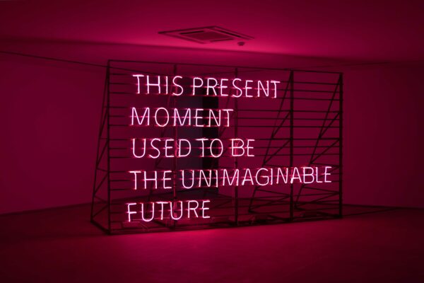 A photo of a light artwork that reads "This present moment used to be the unimaginable future"