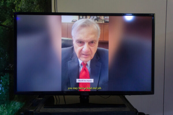A photo of a television displaying a Cameo video of Sheriff Joe Arpaio. The screen is subtitled, "you may have a dead end job"